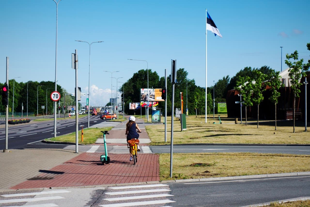 A women is riding a bicycle as a form of commuting. She is avoiding the e-scooter in the middle of the street.